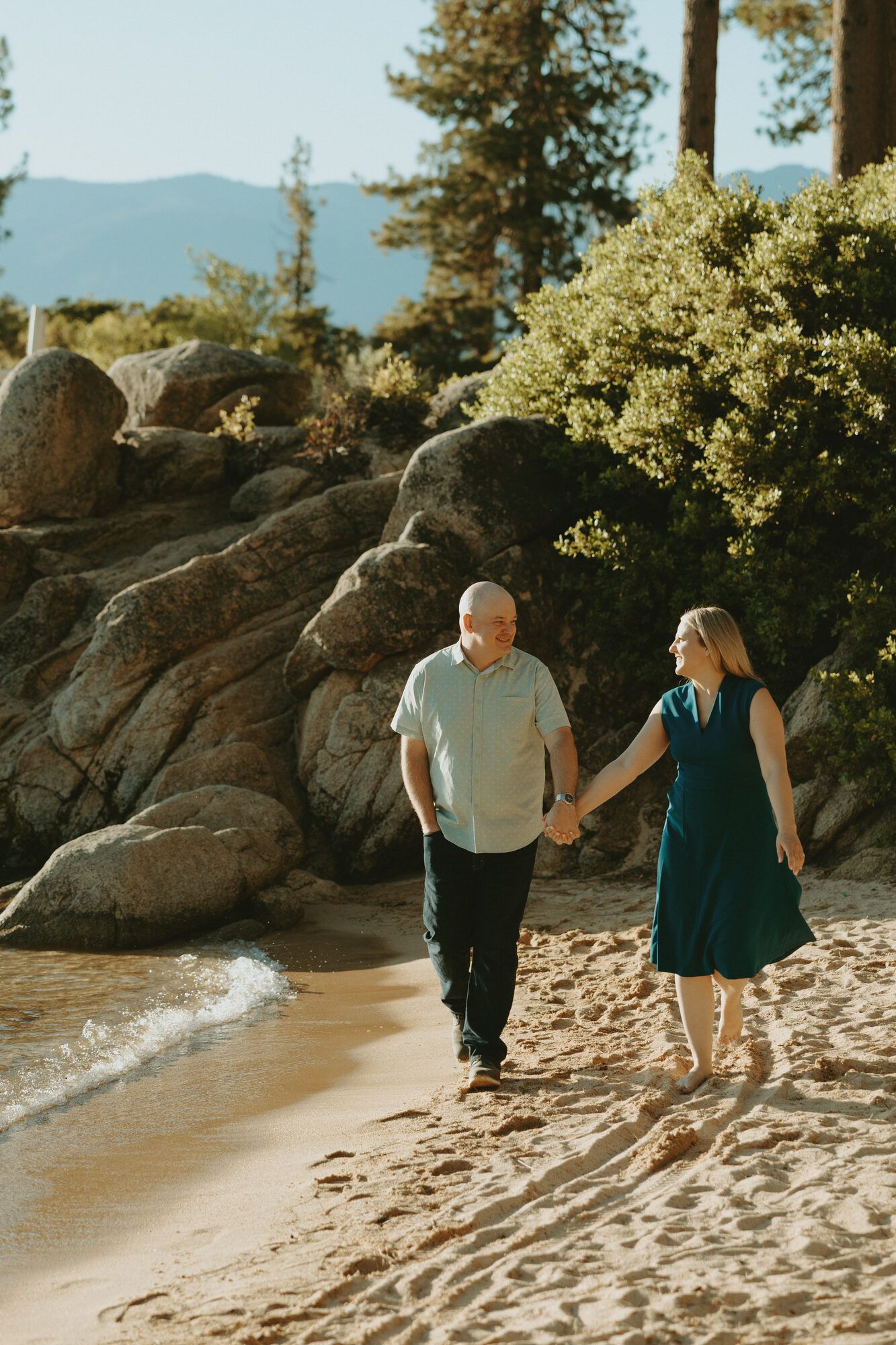 Holding hands on the beach, smiling at each other